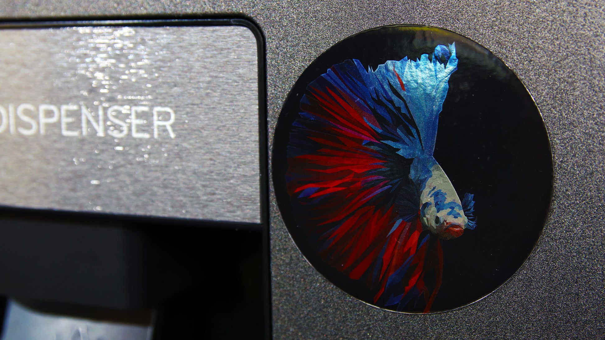 Silver circle magnet custom printed with a fish applied to a silver fridge