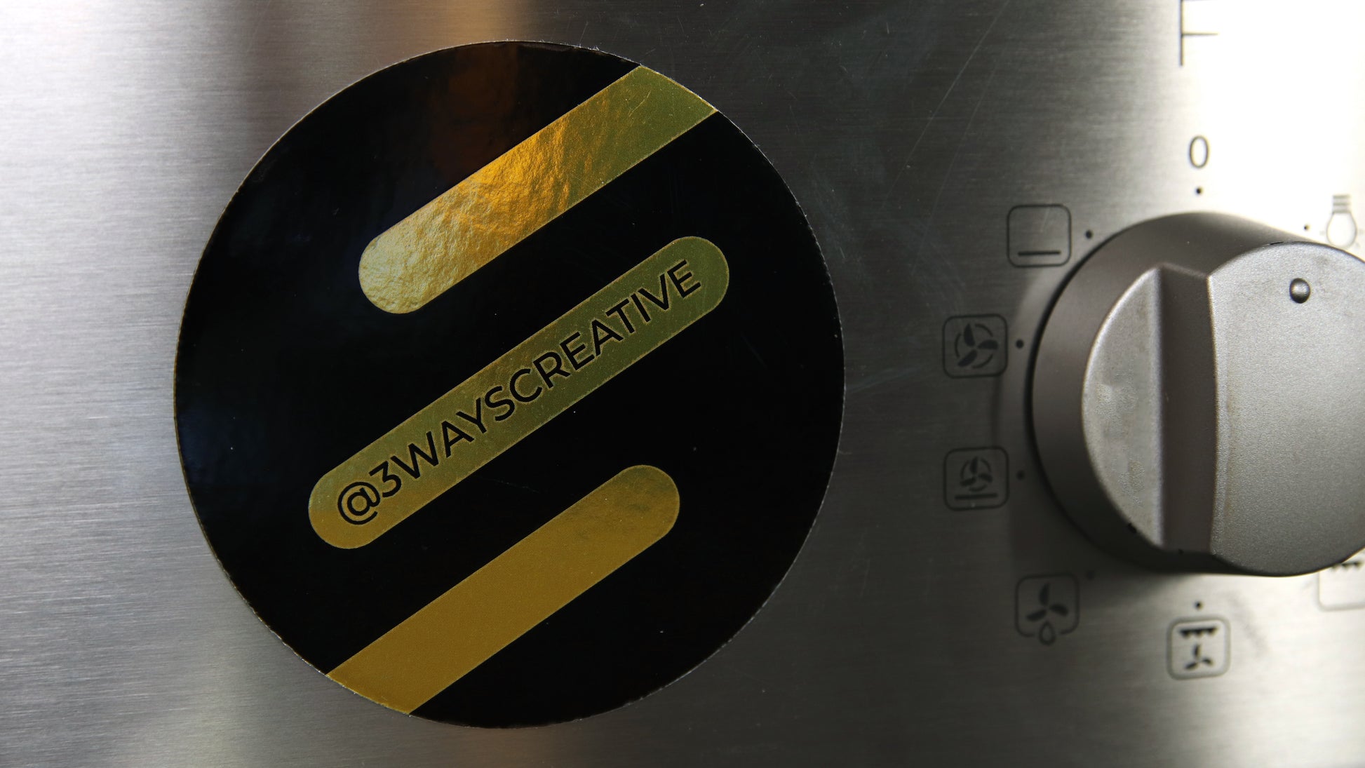 Creative logo on a gold circle magnet stuck to a cooker