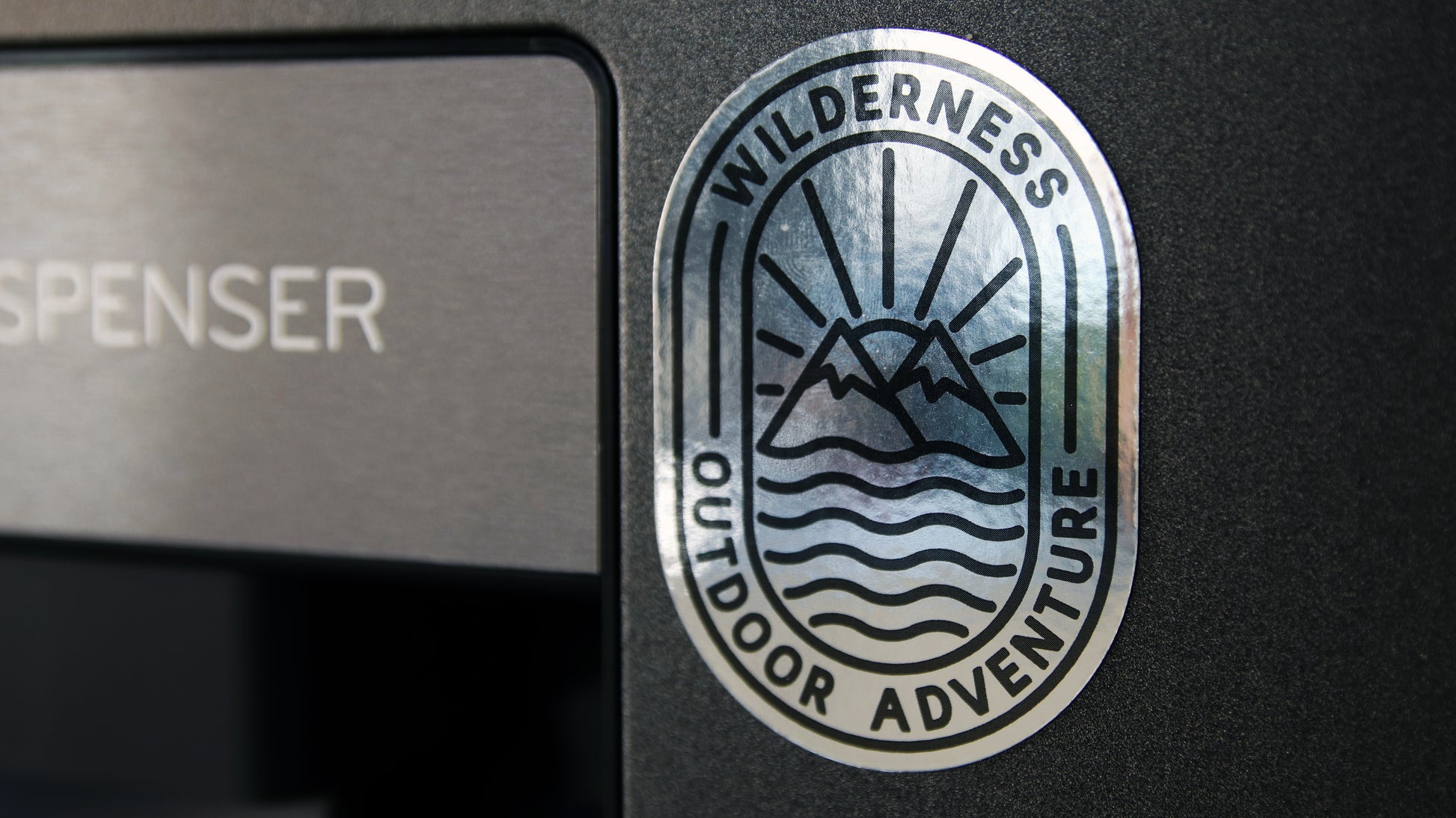 Oval shaped custom printed silver magnet with a black Outdoor Adventure design