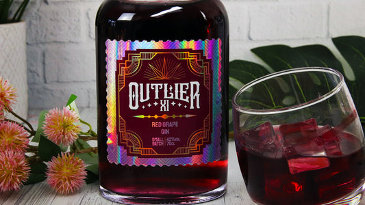 Die cut holographic branding label with gin logo to applied to a bottle next to a tilted glass