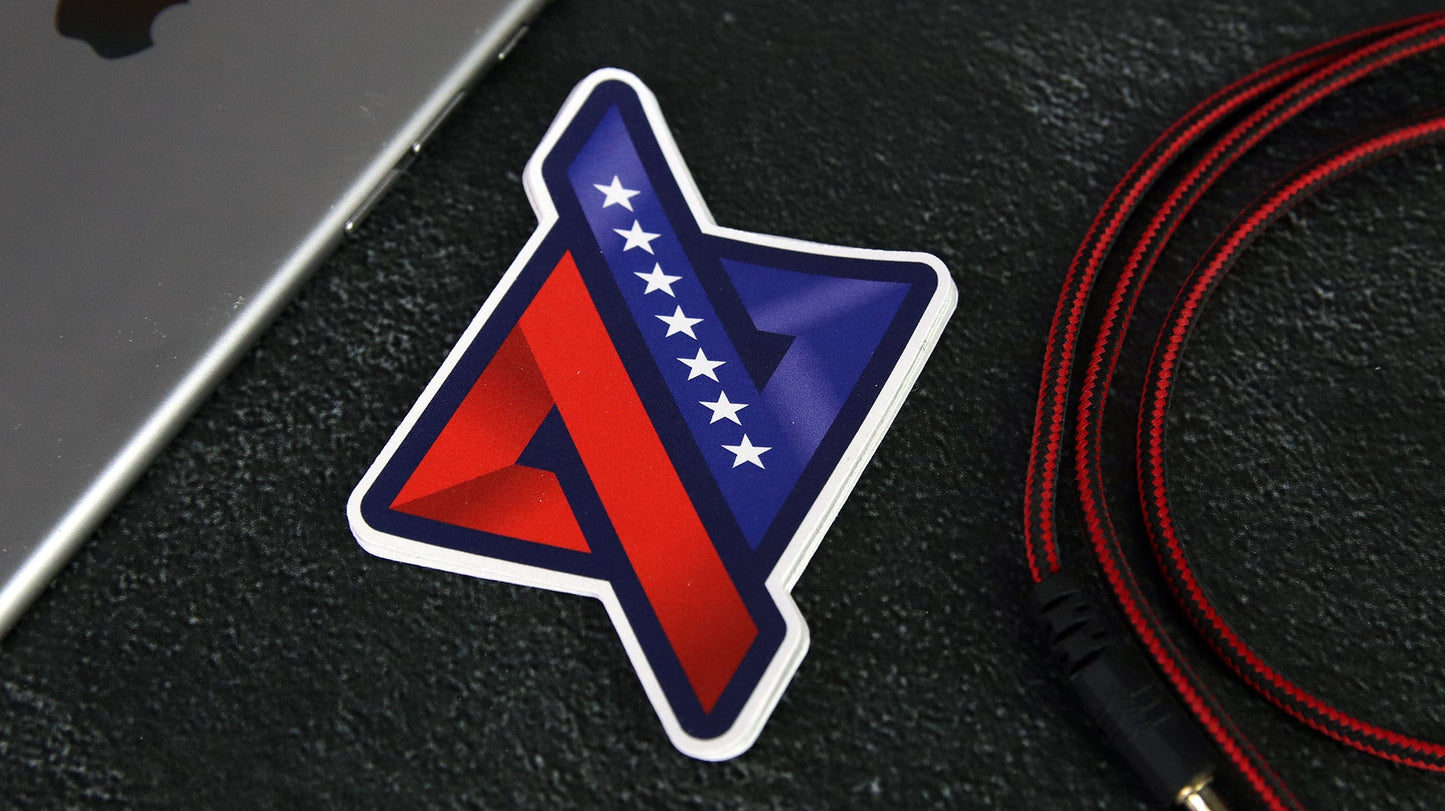 Die cut logo sticker with flag design on a black desk next to a silver iPad