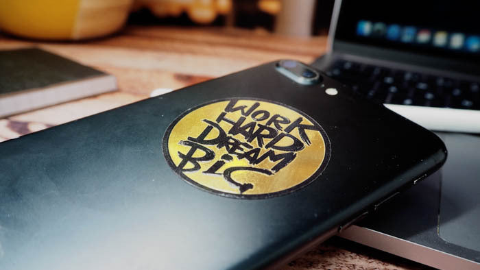 Mirror gold sticker circle shape with work hard dream big applied to an iPhone