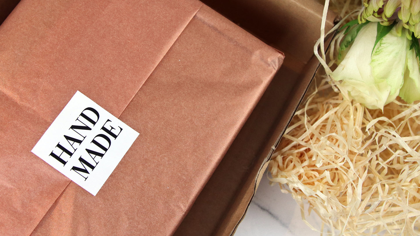 Square white vinyl labels with hand made design used as a packaging seal