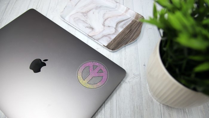 Circle eco-friendly clear stickers with a peace design applied to a silver laptop