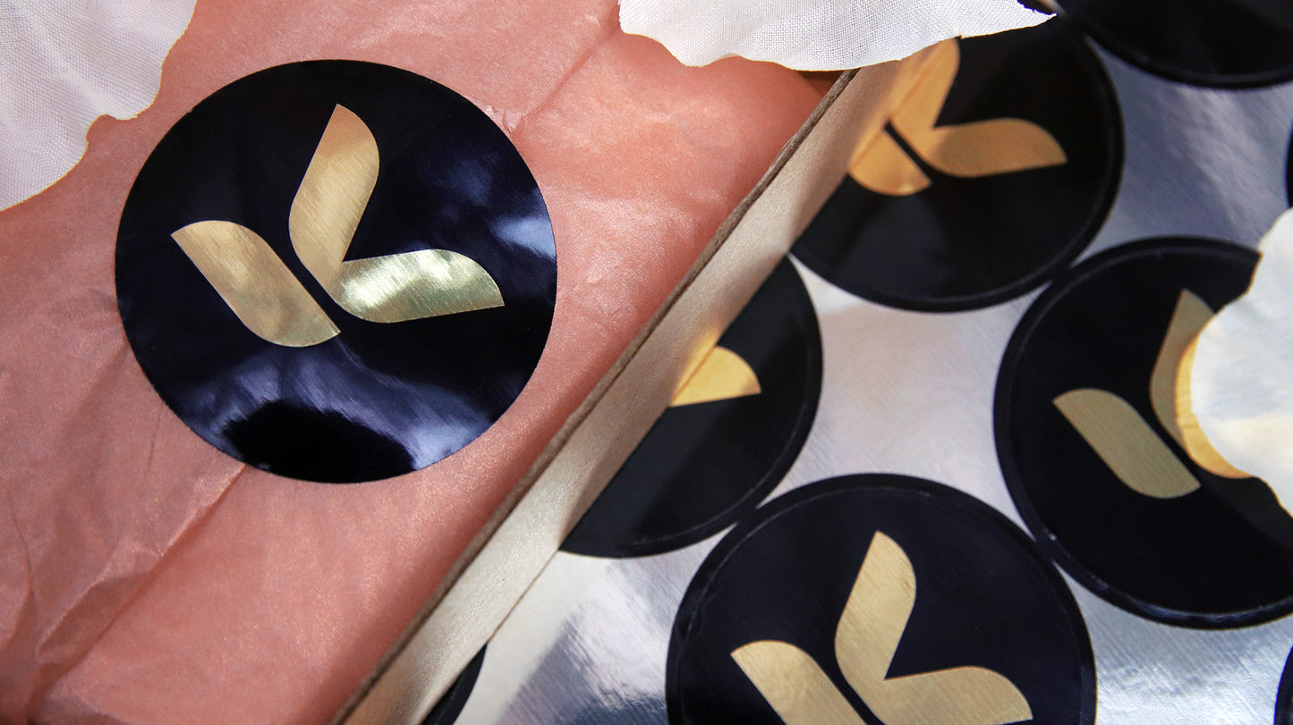 Circle eco-friendly gold labels with signature brand logo applied to seal packaging