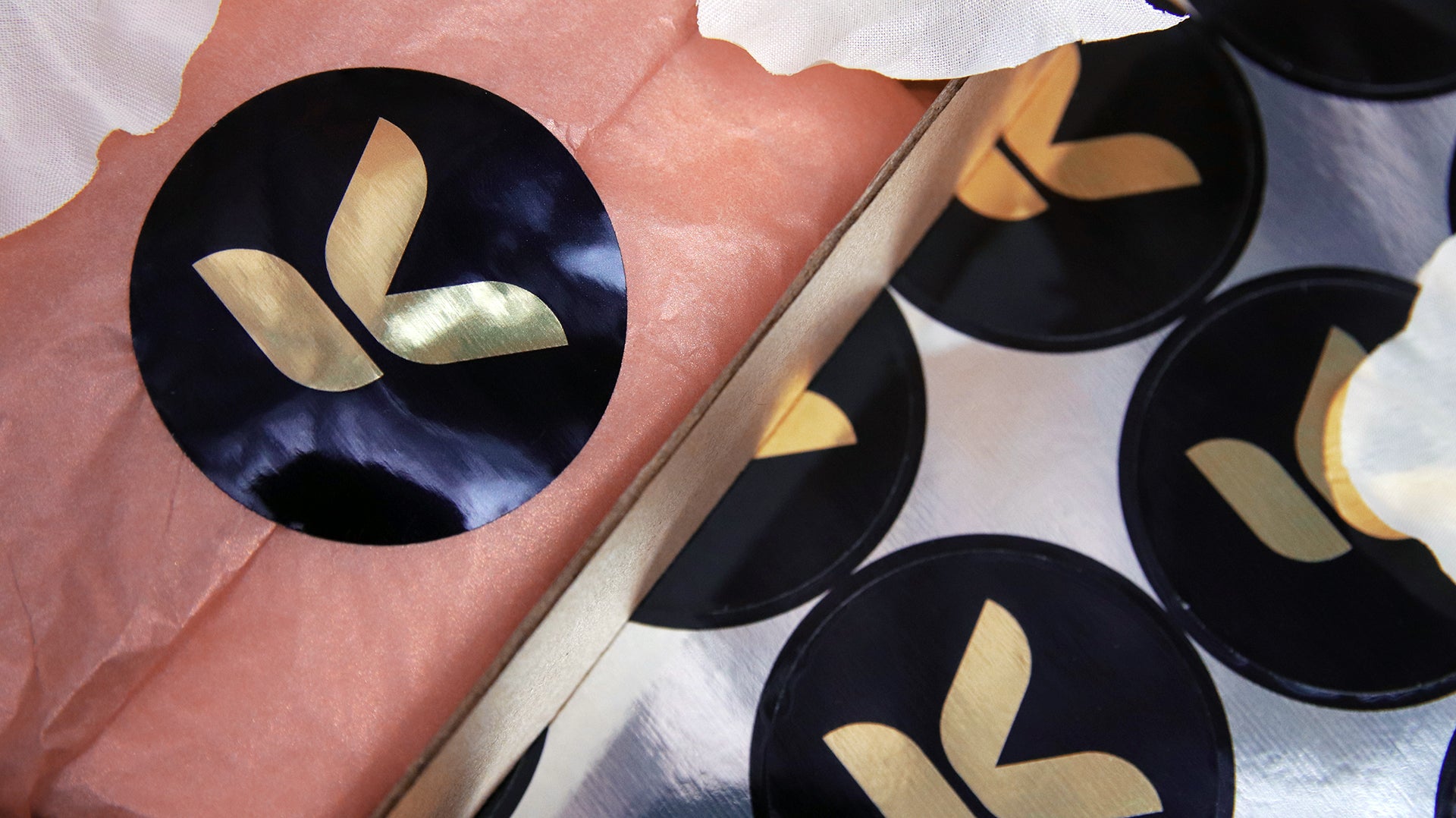 Circle eco-friendly gold labels with signature brand logo applied to seal packaging