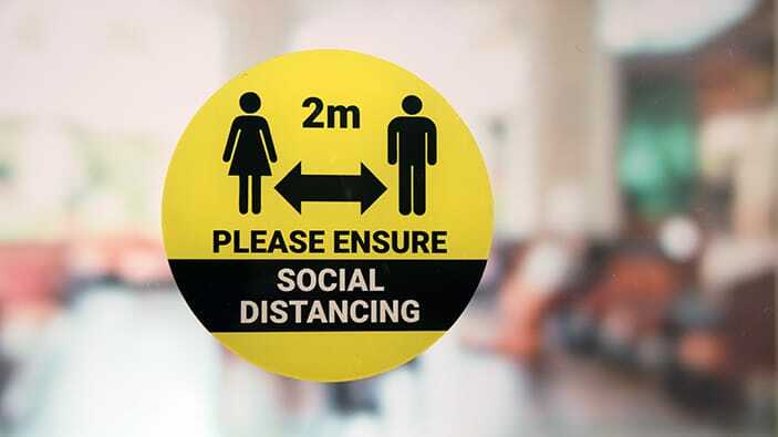 Circle static cling sticker with social distancing design applied to a window