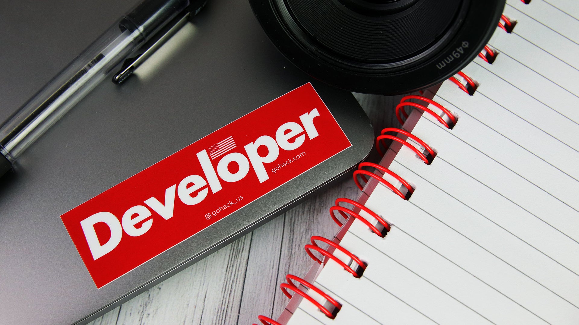 Rectangular white vinyl sticker with developer design applied to a silver laptop