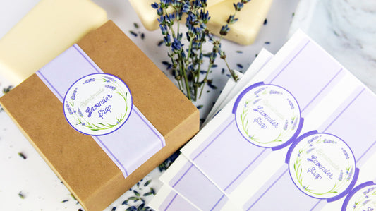 Die-cut biodegradable paper packaging labels applied to a cardboard box filled with lavender soap