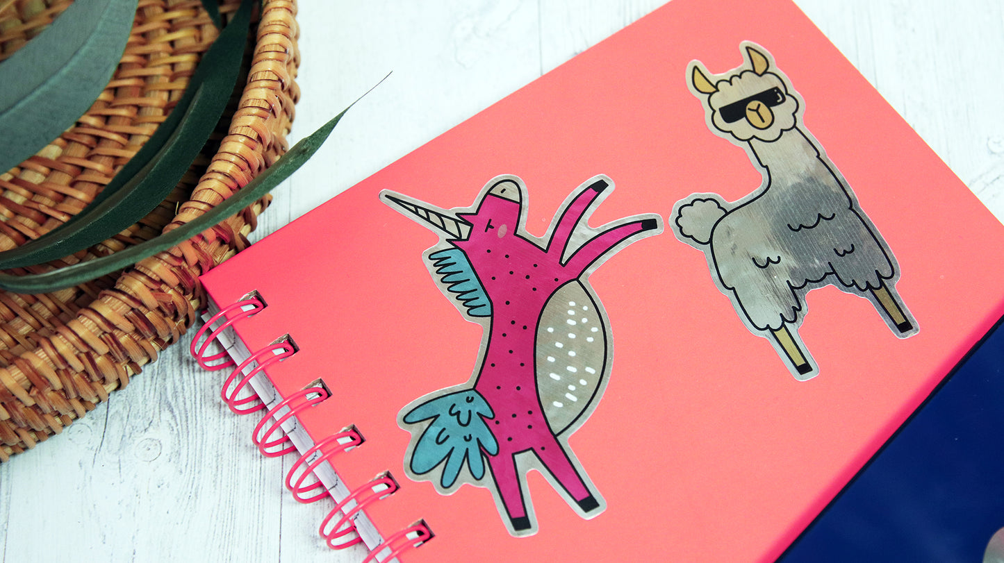 Die cut eco-friendly silver stickers with different designs applied to an orange notebook