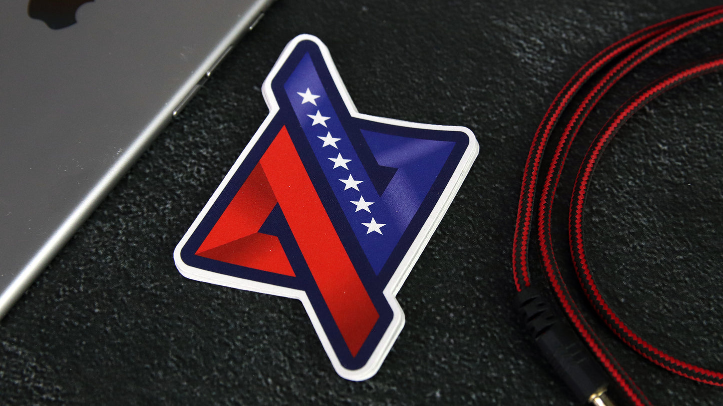 Die cut logo sticker with flag design on a black desk next to a silver iPad