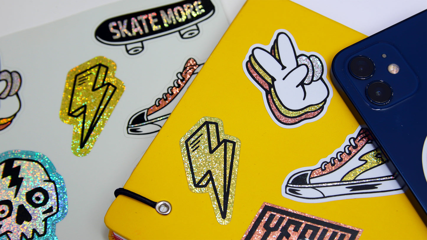 Eco-friendly glitter labels with various designs, some applied to a yellow notebook