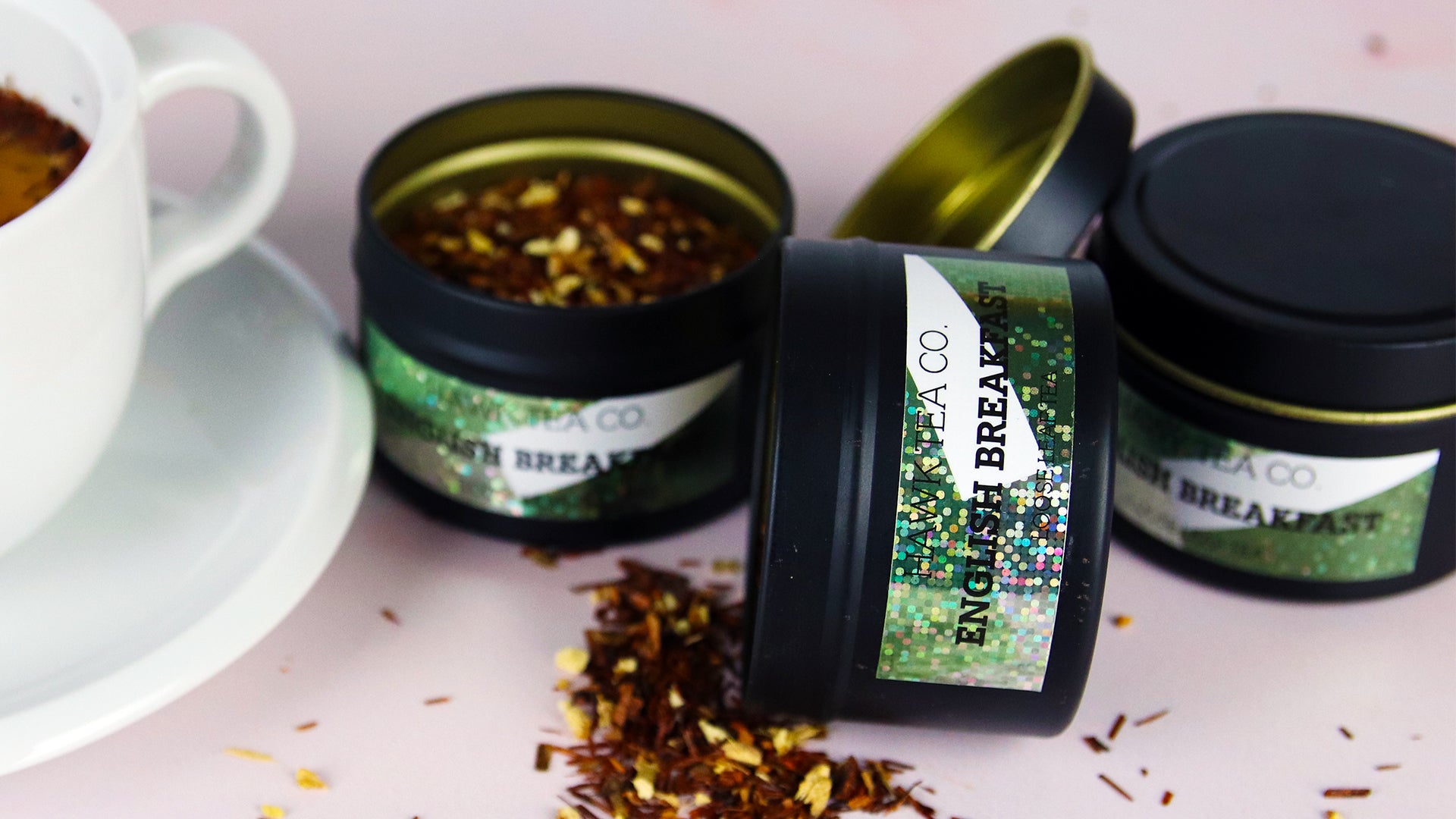 Rectangular glitter stickers applied to black tea tins next to a white mug