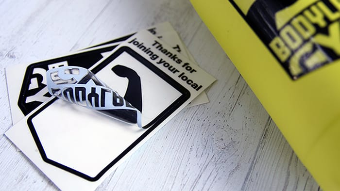 Kiss cut samples printed onto clear vinyl with one applied to a yellow water bottle and one half-peeled