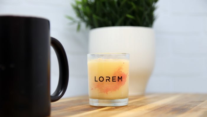 Rectangular eco-friendly clear label applied to a clear candle jar with an orange candle