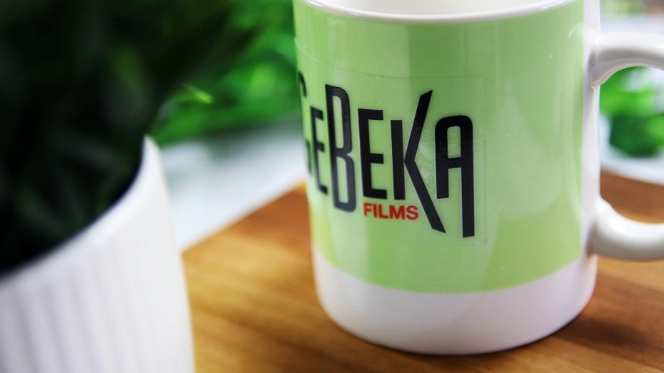 Rectangular transparent sticker with logo applied to a white and green mug