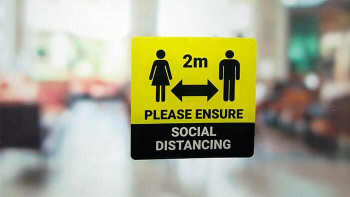 Rounded corner static cling sticker with social distancing design applied to a window