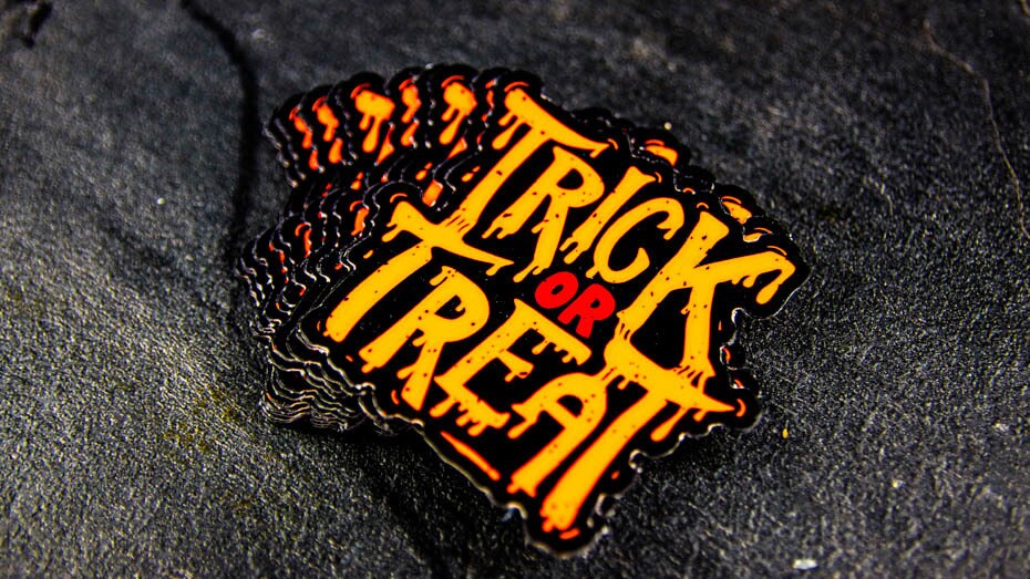 Stack of die cut fluorescent orange labels with trick or treat design on a table