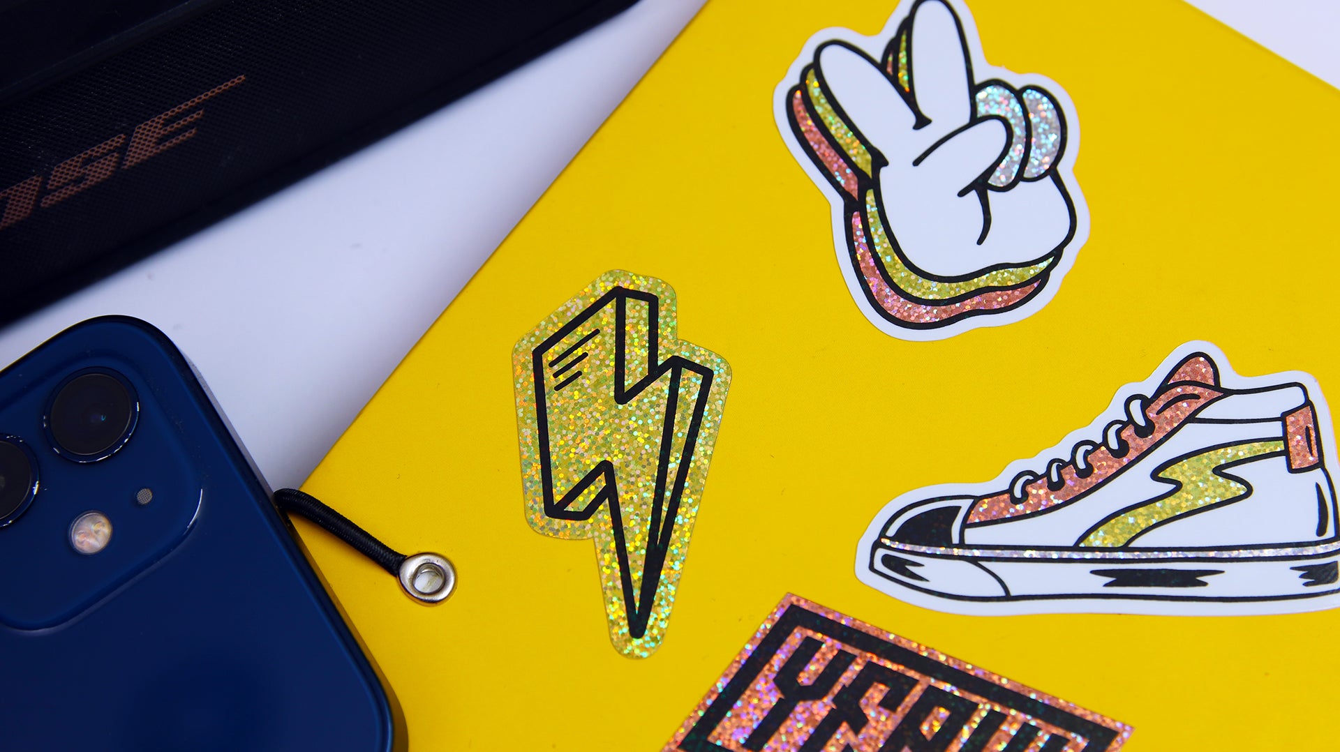 Various die cut eco-friendly glitter stickers with different designs applied to a yellow notebook