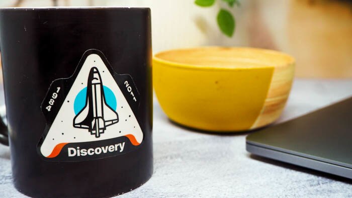 Die cut white vinyl sticker with discovery design applied to black mug