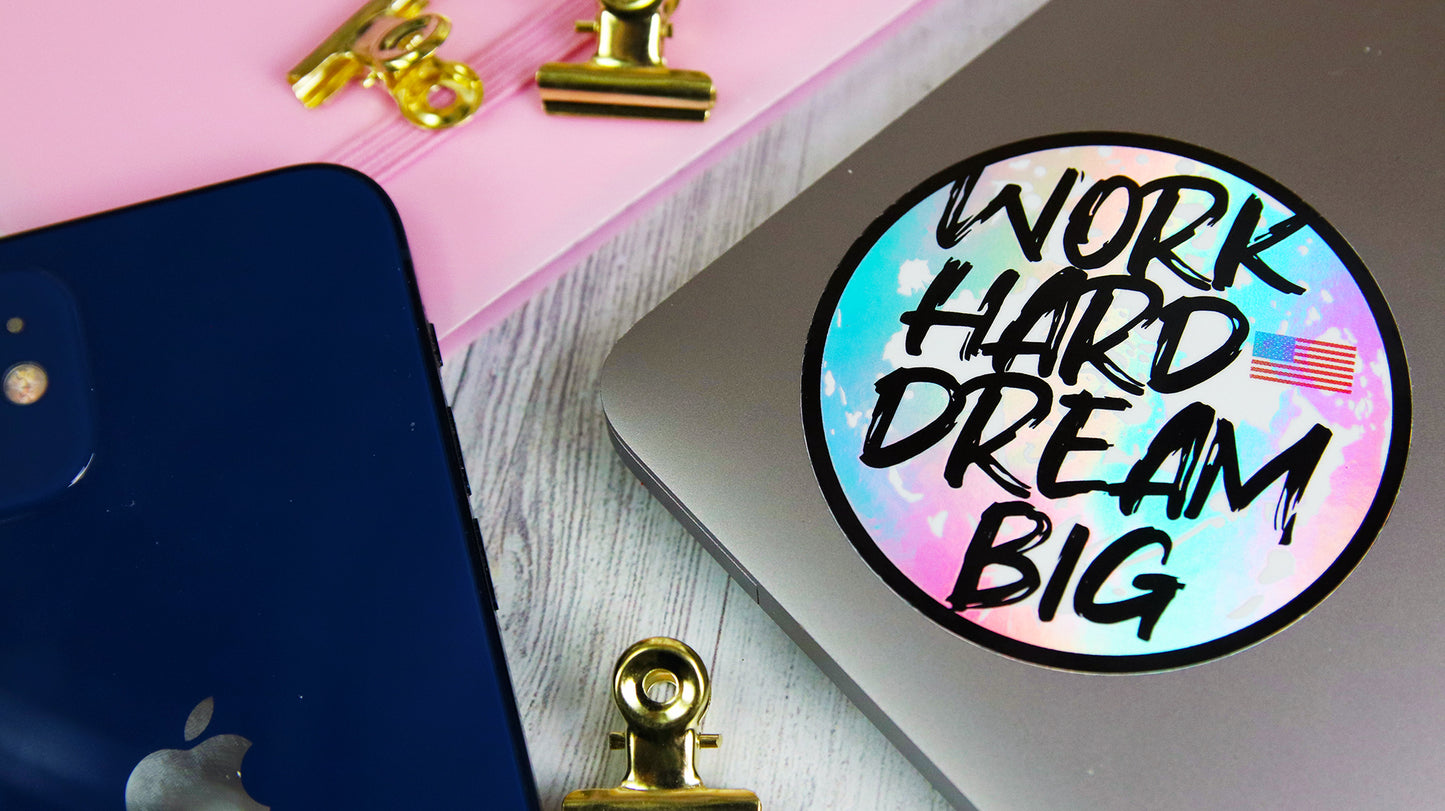Circle holographic sticker with work hard dream big design applied to a silver laptop