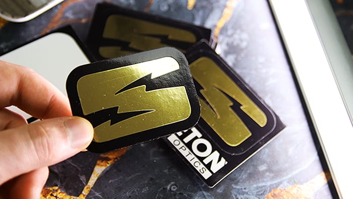 Stack of peeled kiss cut stickers printed into mirror gold with Skeleton logo